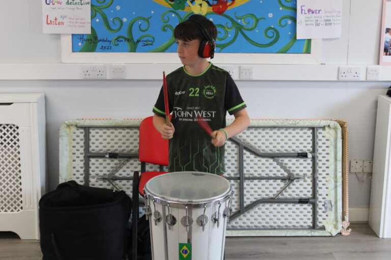 Young Person drumming on the main drum at the top of the room